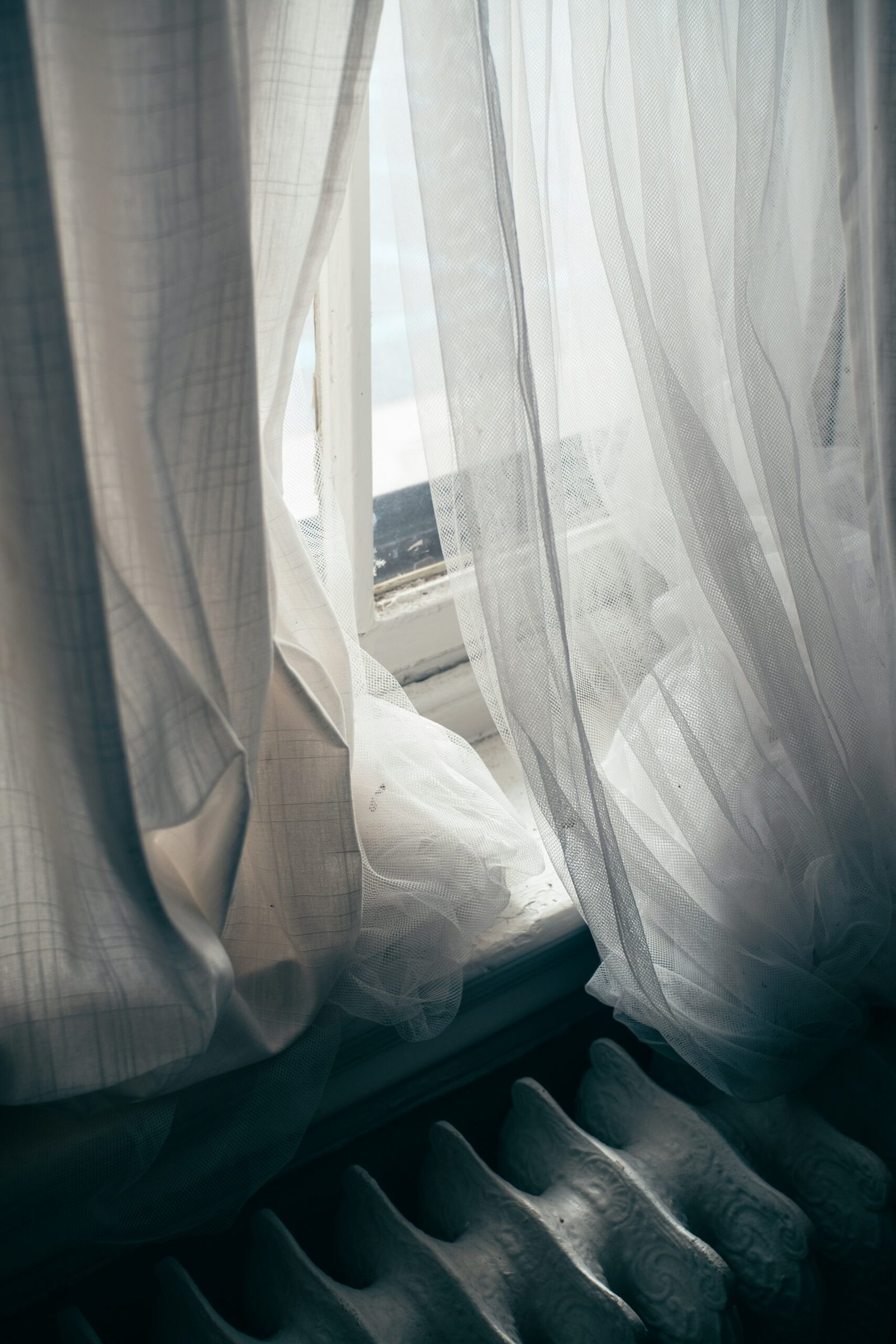 a window with sheer curtains and a window sill